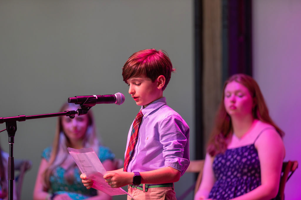 boy reads poem on stage at celebration of young writers