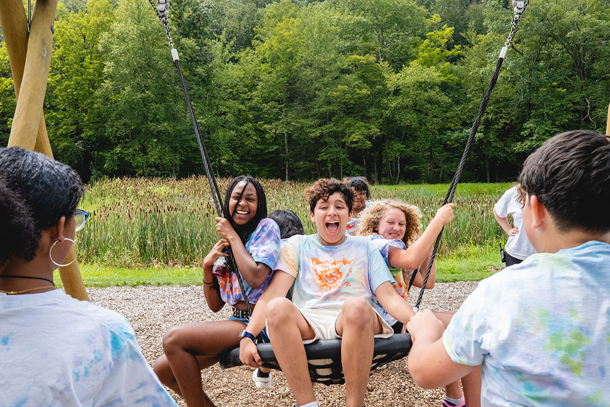 students smiling on swing at summer program